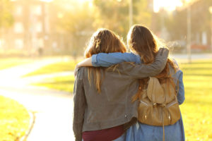 two women walking with their arms around each other in support